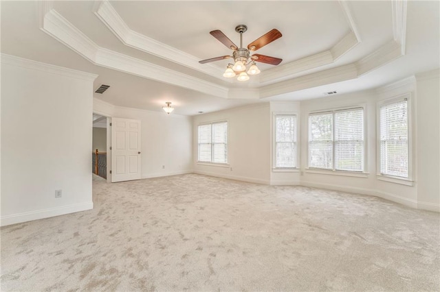 empty room featuring ceiling fan, ornamental molding, a tray ceiling, and light carpet