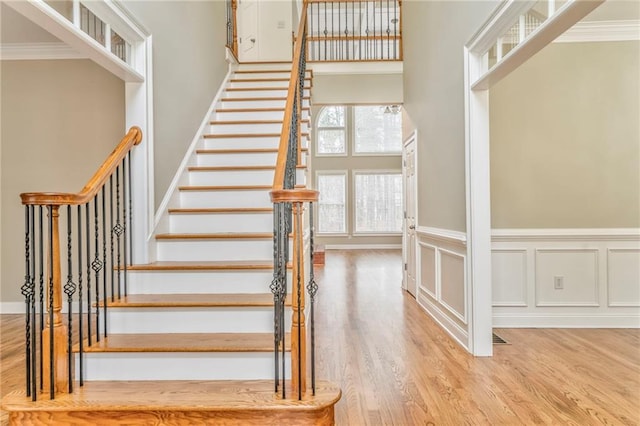 staircase with hardwood / wood-style flooring, ornamental molding, and a towering ceiling