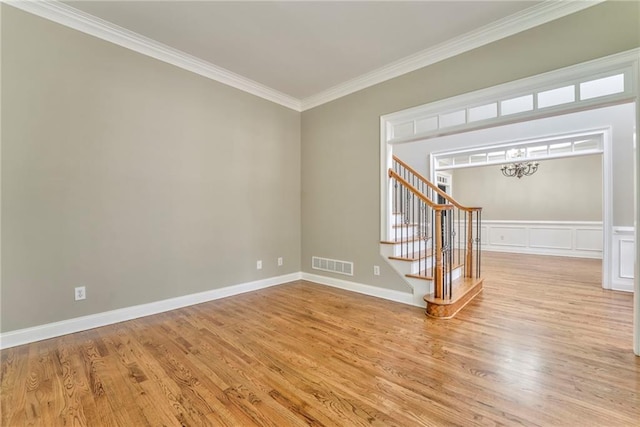 empty room with ornamental molding and light hardwood / wood-style flooring