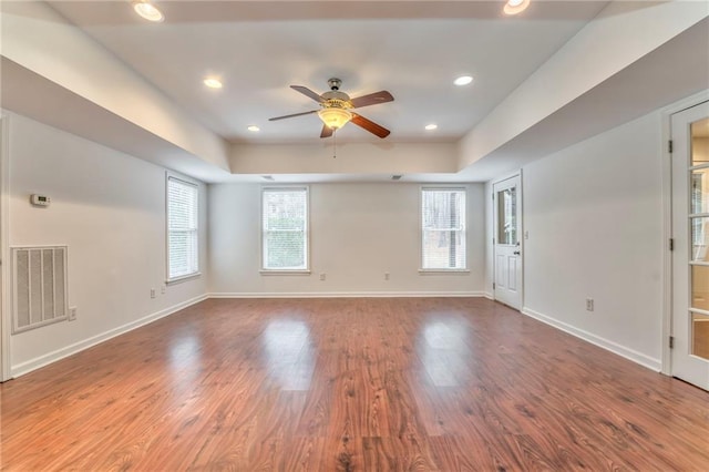 unfurnished room featuring hardwood / wood-style floors, a tray ceiling, and ceiling fan