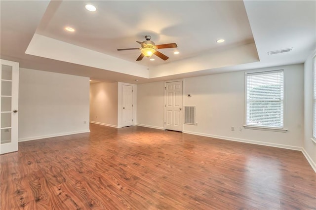 unfurnished room featuring dark wood-type flooring, a raised ceiling, and ceiling fan