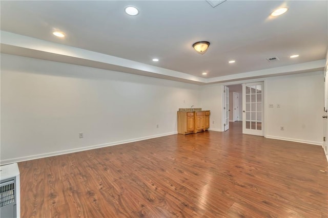 interior space featuring dark hardwood / wood-style flooring, a tray ceiling, heating unit, and french doors