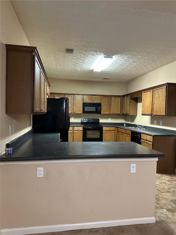 kitchen with a textured ceiling, black appliances, and kitchen peninsula