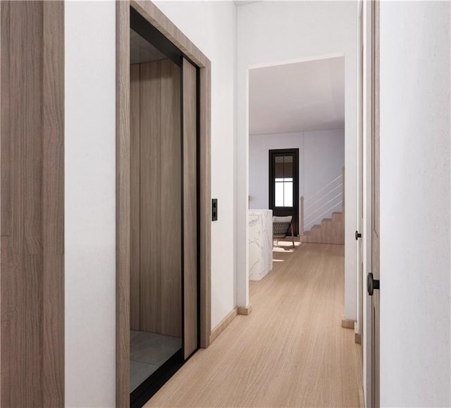 hallway with elevator and light hardwood / wood-style floors