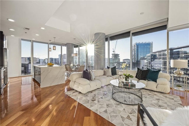 living room featuring a wealth of natural light, visible vents, a city view, expansive windows, and light wood finished floors