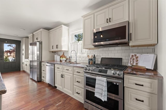 kitchen with appliances with stainless steel finishes, white cabinets, tasteful backsplash, and sink