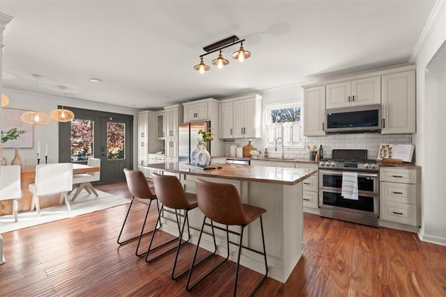 kitchen with tasteful backsplash, a center island, hanging light fixtures, appliances with stainless steel finishes, and white cabinets