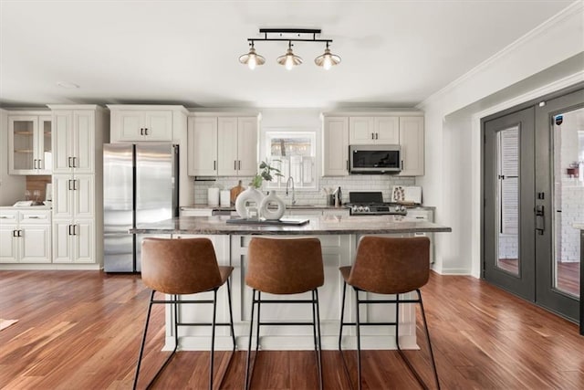 kitchen with white cabinetry, appliances with stainless steel finishes, tasteful backsplash, french doors, and stone countertops