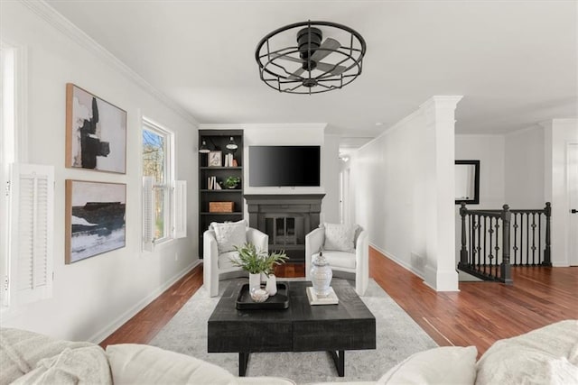 living room featuring ceiling fan, wood-type flooring, built in features, and crown molding