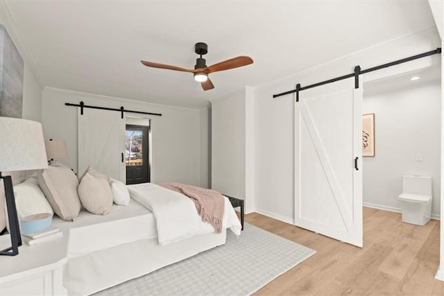 bedroom featuring ceiling fan, light hardwood / wood-style floors, a barn door, and crown molding