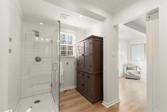 bathroom featuring ornamental molding, hardwood / wood-style flooring, and walk in shower