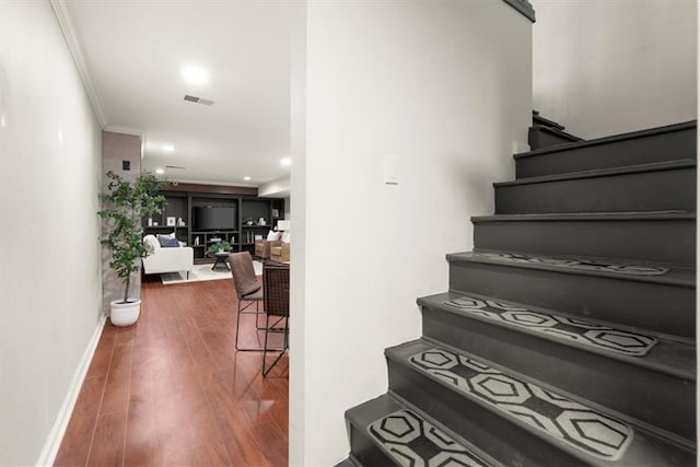 staircase with crown molding and hardwood / wood-style floors