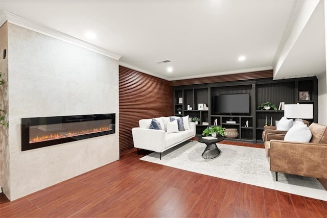 living room with a fireplace, crown molding, and hardwood / wood-style flooring