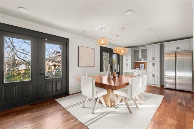 dining space featuring dark hardwood / wood-style flooring, ornamental molding, and french doors