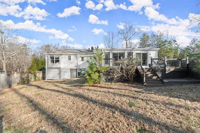 rear view of house with a wooden deck, a yard, and a sunroom