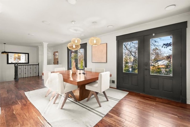 dining space with decorative columns, dark wood-type flooring, and crown molding