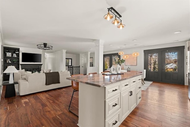 kitchen with french doors, a kitchen island, white cabinets, and light stone countertops