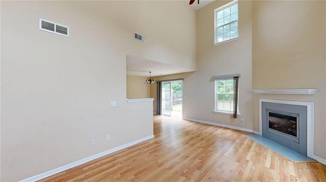 176 Silver Fox Trl, Dallas, GA 30157 - unfurnished living room with healthy amount of natural light, light wood-style flooring, baseboards, a fireplace with flush hearth, and a towering ceiling