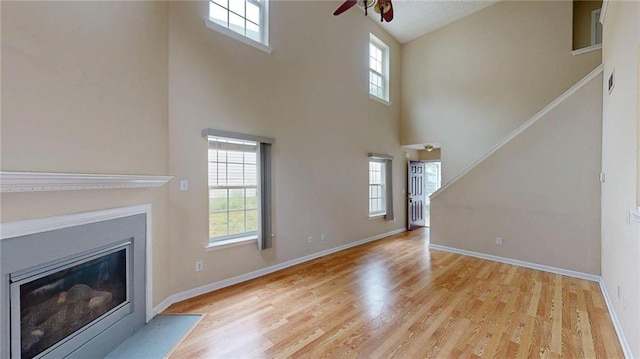 176 Silver Fox Trl, Dallas, GA 30157 - unfurnished living room featuring a high ceiling, ceiling fan, wood finished floors, a fireplace with flush hearth, and stairs