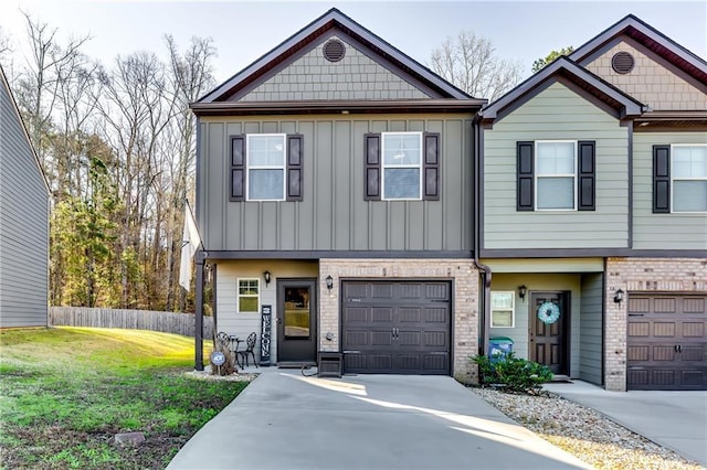 view of property featuring fence, an attached garage, concrete driveway, a front lawn, and board and batten siding
