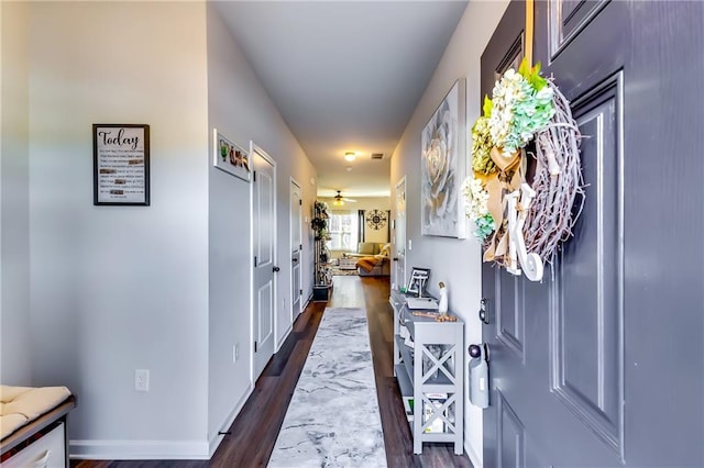 corridor featuring dark wood-type flooring and baseboards
