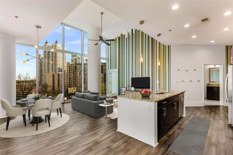 kitchen featuring dark hardwood / wood-style flooring, ceiling fan with notable chandelier, white fridge, and a center island with sink