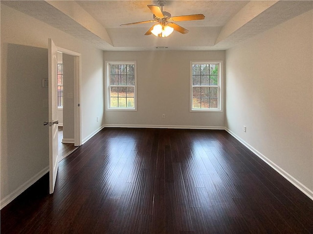 unfurnished room featuring ceiling fan, a tray ceiling, and dark hardwood / wood-style flooring