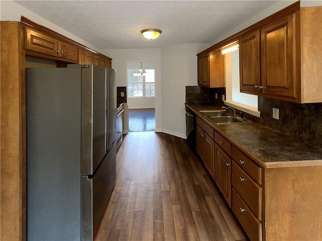 kitchen with appliances with stainless steel finishes, tasteful backsplash, sink, dark wood-type flooring, and a textured ceiling