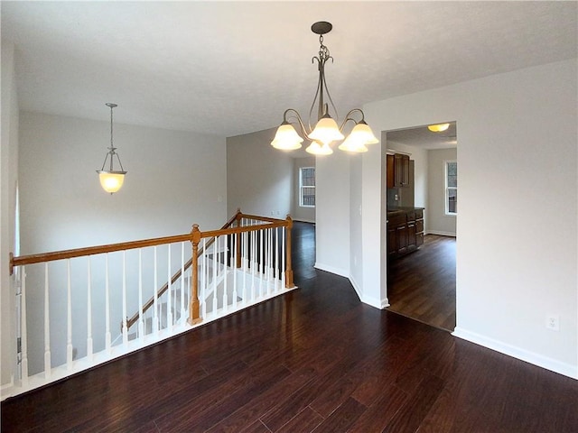 empty room featuring a notable chandelier and dark hardwood / wood-style flooring