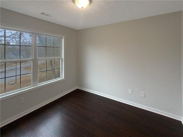 spare room with a wealth of natural light and dark hardwood / wood-style floors