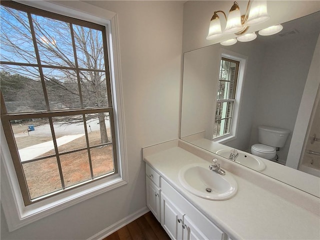 bathroom with vanity, wood-type flooring, an inviting chandelier, and toilet