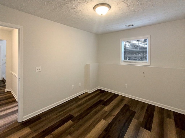 empty room featuring dark hardwood / wood-style flooring and a textured ceiling