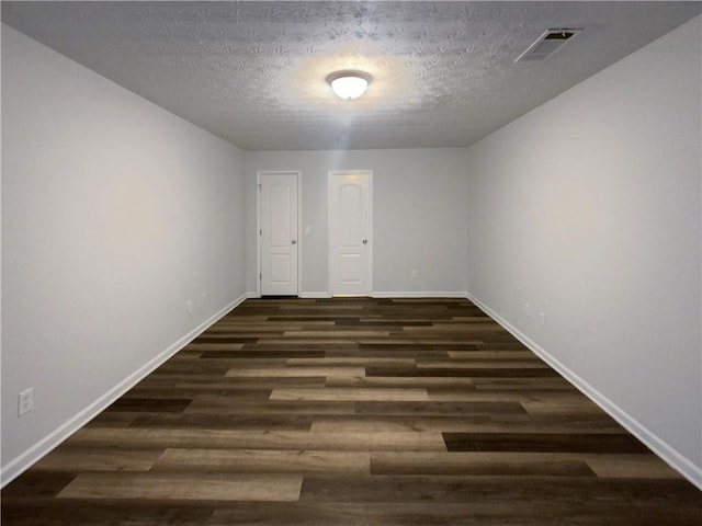 unfurnished room with dark wood-type flooring and a textured ceiling