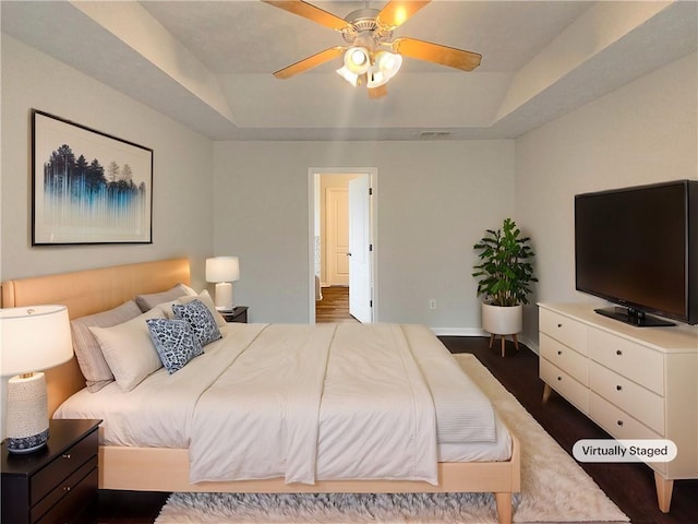 bedroom featuring dark wood-type flooring, ceiling fan, and a raised ceiling