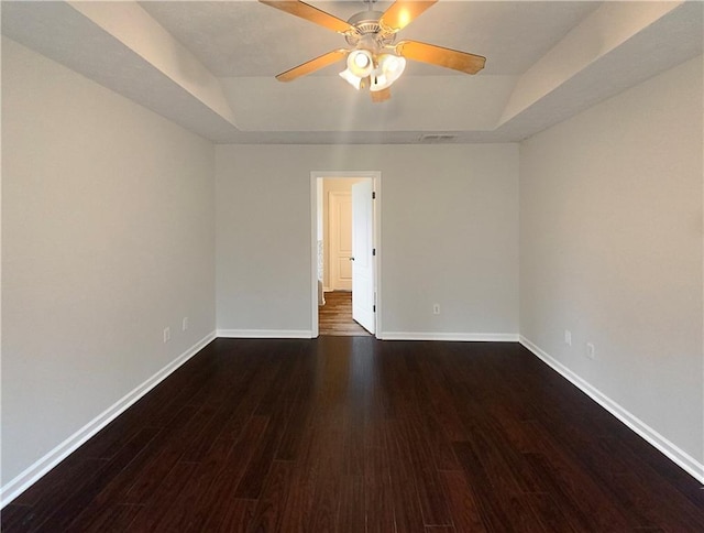 spare room with a raised ceiling, dark hardwood / wood-style floors, and ceiling fan