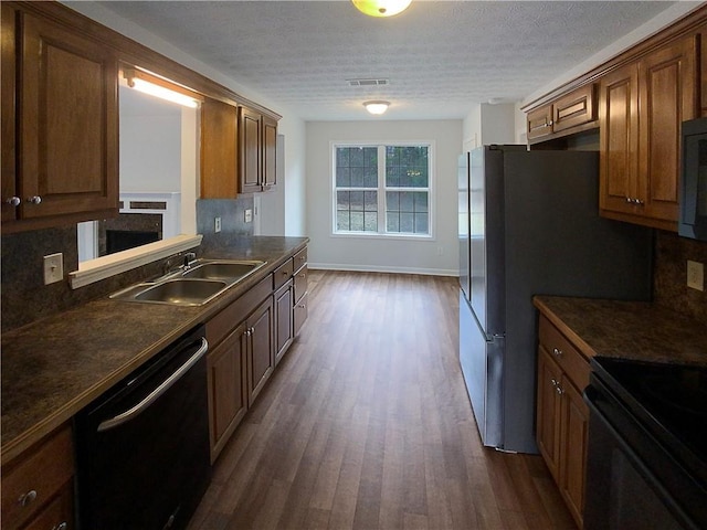 kitchen with sink, black appliances, a textured ceiling, dark hardwood / wood-style flooring, and backsplash