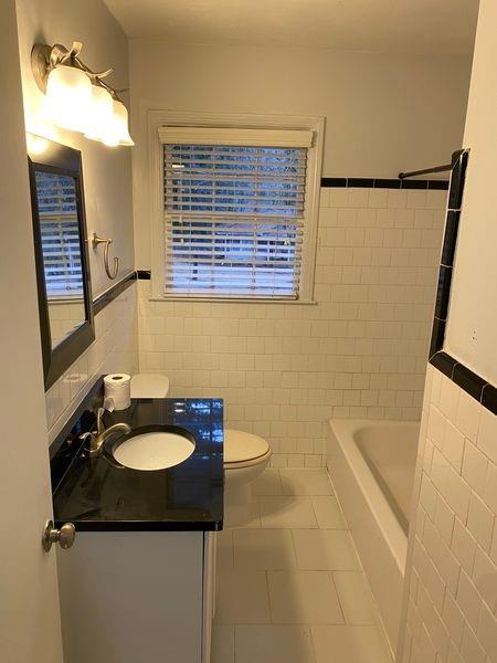 bathroom featuring tile patterned floors, a washtub, tile walls, and vanity