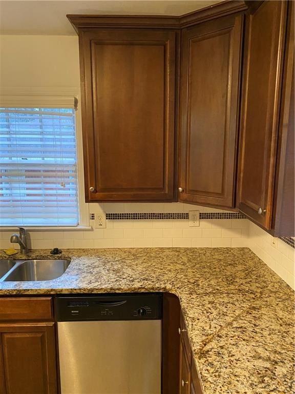 kitchen featuring light stone countertops, dishwasher, sink, and decorative backsplash