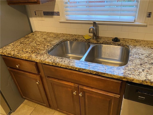 room details featuring tasteful backsplash, stainless steel dishwasher, light stone countertops, and sink