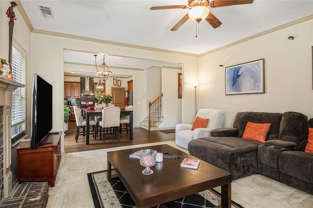 living room with a ceiling fan, visible vents, light wood finished floors, stairs, and crown molding