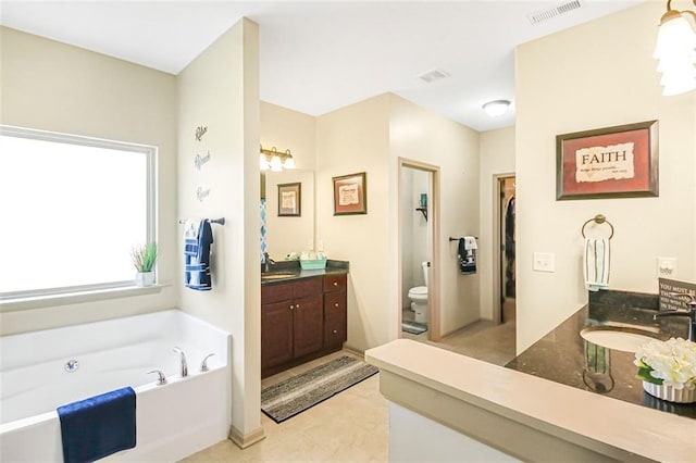 bathroom featuring vanity, toilet, a bath, and visible vents