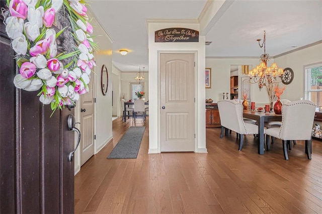 foyer entrance with a chandelier, ornamental molding, and hardwood / wood-style flooring