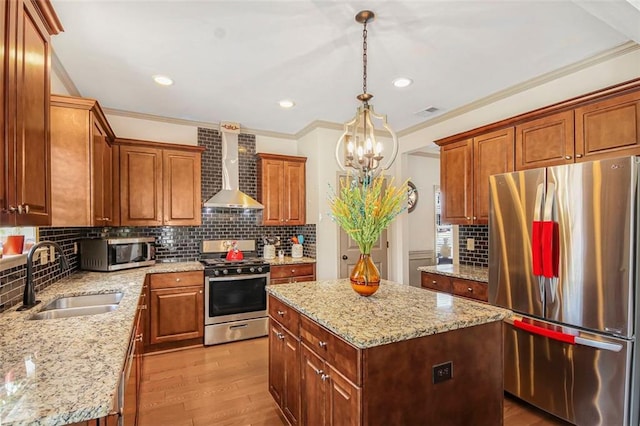 kitchen featuring light wood-style flooring, a sink, decorative backsplash, appliances with stainless steel finishes, and wall chimney exhaust hood