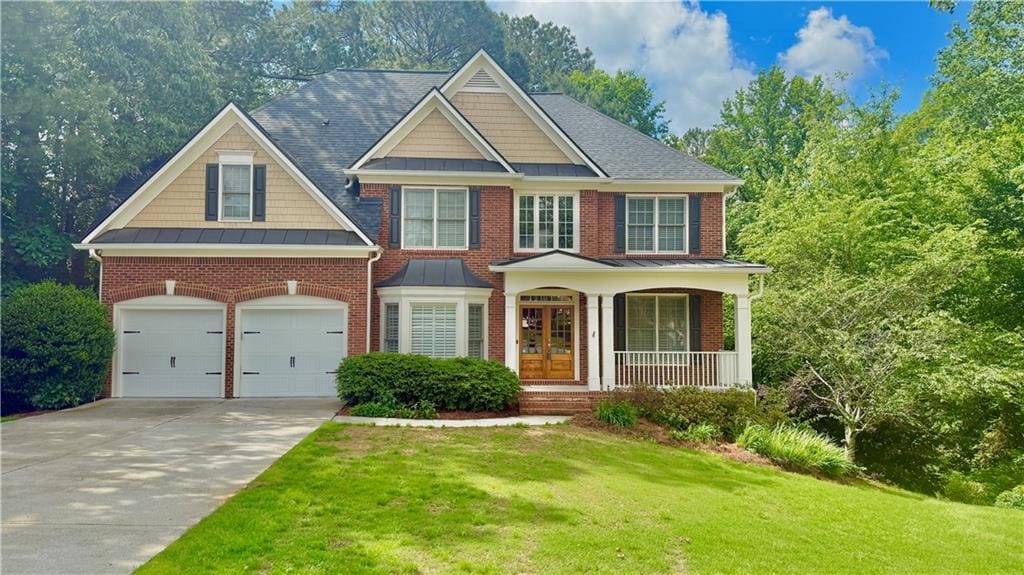 view of front of house with a front yard, driveway, a porch, and brick siding