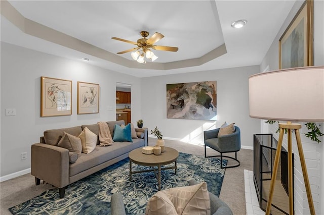 living area with baseboards, a raised ceiling, and carpet