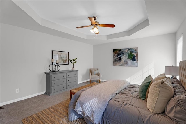 carpeted bedroom with ceiling fan, baseboards, and a tray ceiling