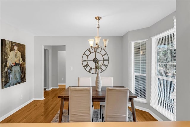 dining room featuring a notable chandelier, wood finished floors, and baseboards