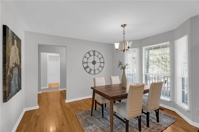 dining room featuring baseboards, an inviting chandelier, and light wood-style flooring