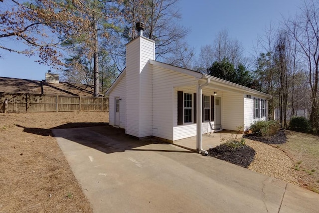 view of side of home with a patio, a chimney, and fence