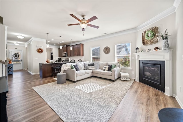 living room with light hardwood / wood-style flooring, ceiling fan, crown molding, and a premium fireplace